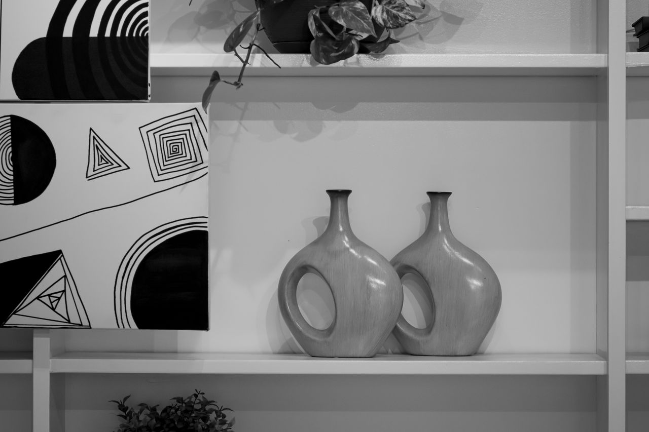 Elegant black and white decor featuring abstract art and stylish vases on a shelf.