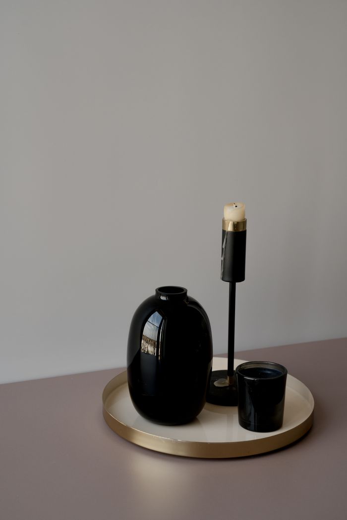 A modern minimalist display featuring a black vase and a candle on a tray, perfect for interior decor.